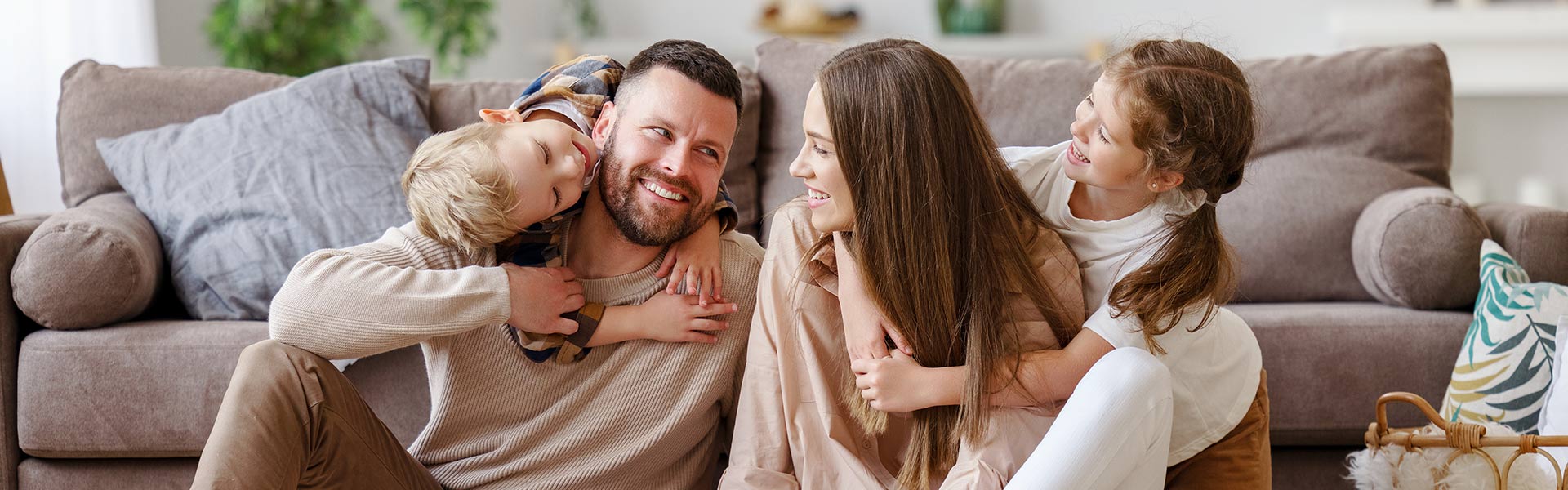 Happy family mother father and children at home on floor next to sofa